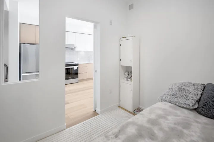 Bedroom with freestanding refrigerator and light wood finished floors