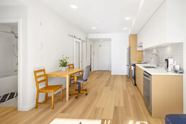 Dual tone kitchen featuring a barn door, modern cabinets, light wood-type flooring, stainless steel appliances, and light stone countertops
