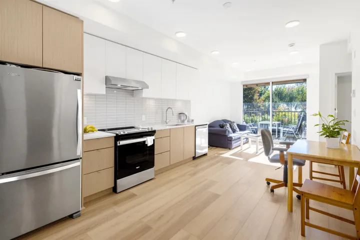 Dual tone kitchen featuring stainless steel appliances, light wood-type flooring, backsplash, modern cabinets, and open floor plan