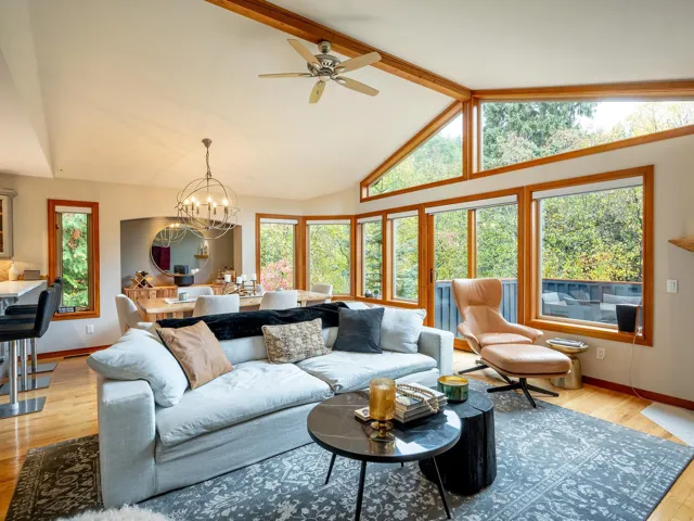 Living room featuring beamed ceiling, light wood-style floors, high vaulted ceiling, a chandelier, and ceiling fan