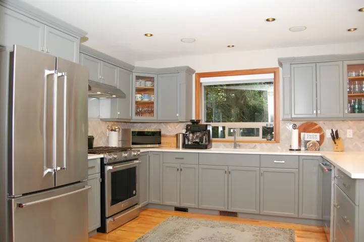 Kitchen featuring glass insert cabinets, appliances with stainless steel finishes, gray cabinets, light wood-style floors, and under cabinet range hood