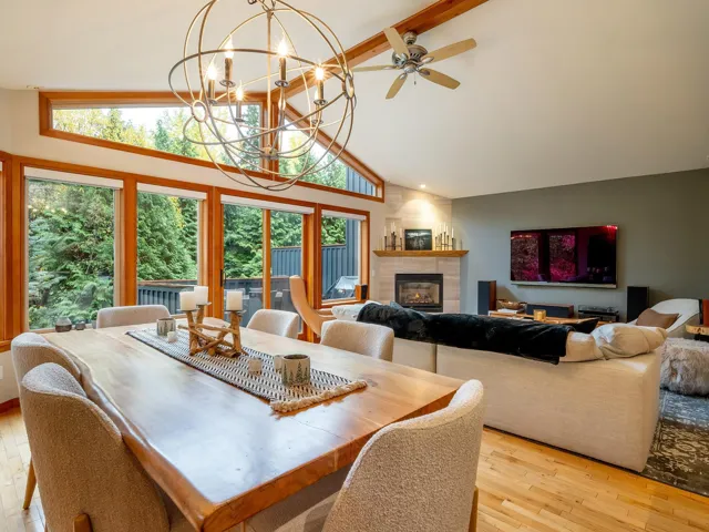 Dining room featuring a tiled fireplace, beamed ceiling, high vaulted ceiling, light wood finished floors, and a chandelier