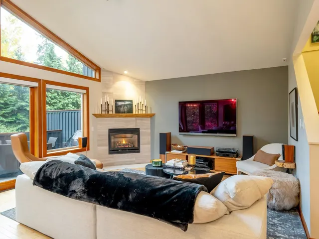Living area with a tiled fireplace, wood finished floors, and lofted ceiling