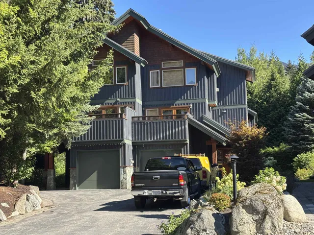View of front of house with a balcony, driveway, a garage, and stone siding