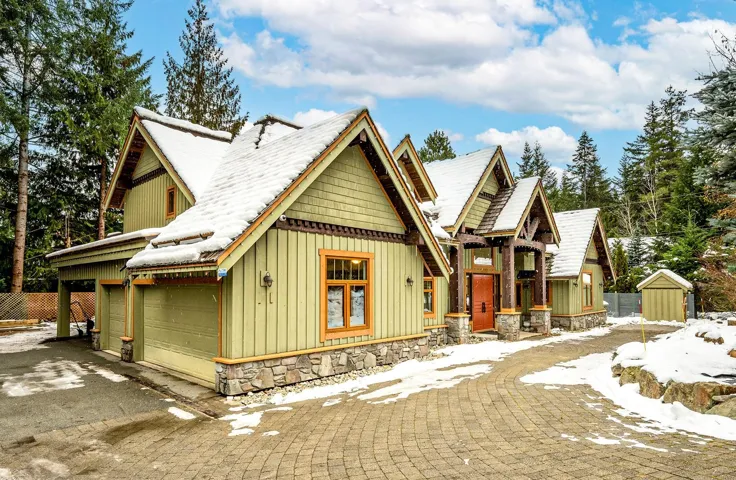 View of front of house featuring board and batten siding, a garage, stone siding, driveway, and an outbuilding