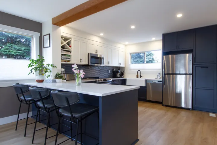 Kitchen with a breakfast bar, stainless steel appliances, light countertops, white cabinetry, and a peninsula