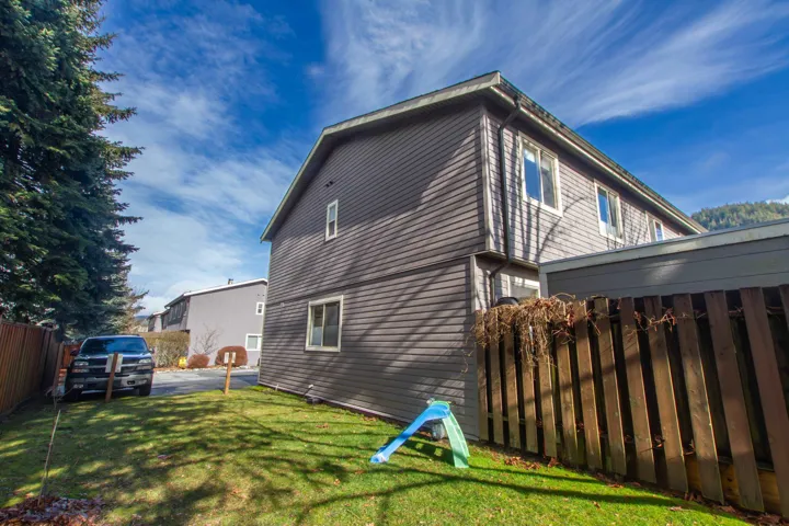 Rear view of house featuring fence and a lawn