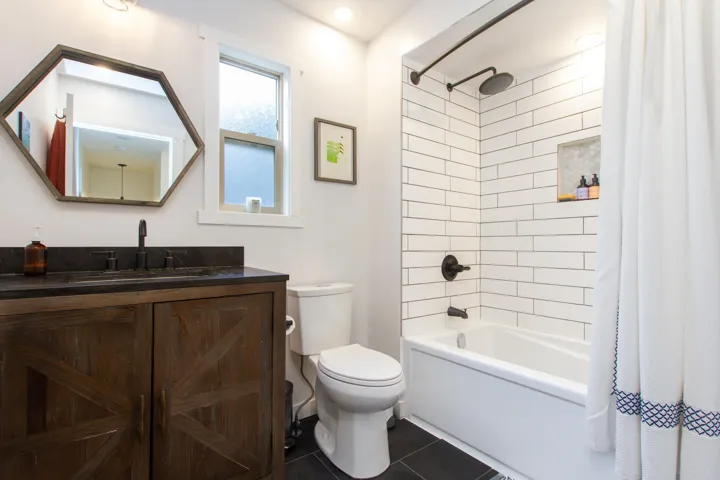 Bathroom featuring tile patterned flooring, shower / bathtub combination with curtain, toilet, and vanity
