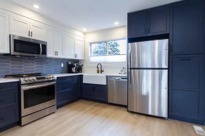 Kitchen with a sink, stainless steel appliances, light countertops, and white cabinets
