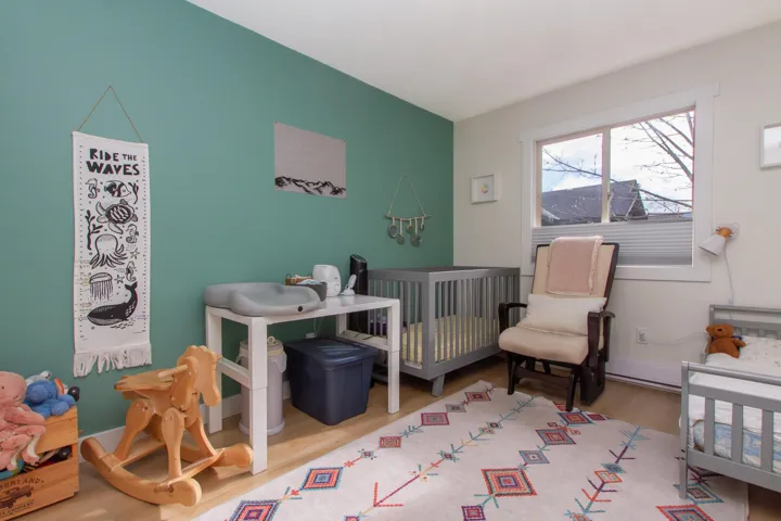 Bedroom with a nursery area, baseboards, and wood finished floors