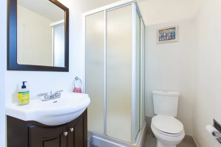Full ensuite bathroom with toilet, a stall shower, tile patterned flooring, and vanity