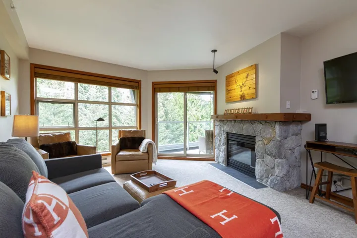Carpeted living area featuring a stone fireplace