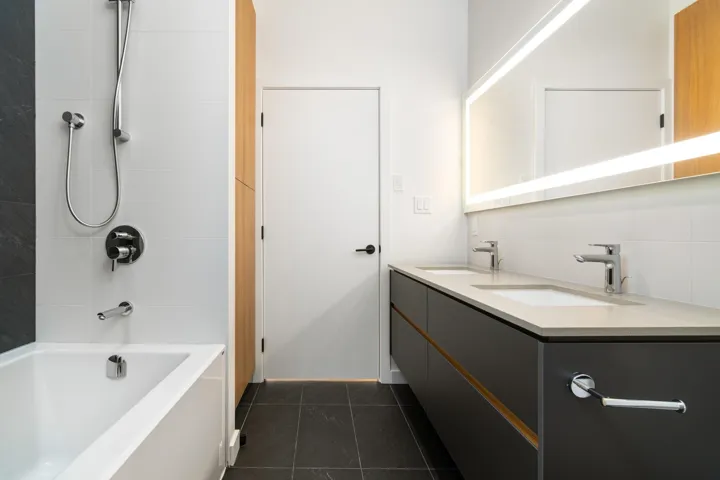 Bathroom featuring double vanity, bathtub / shower combination, tile patterned flooring, and a sink