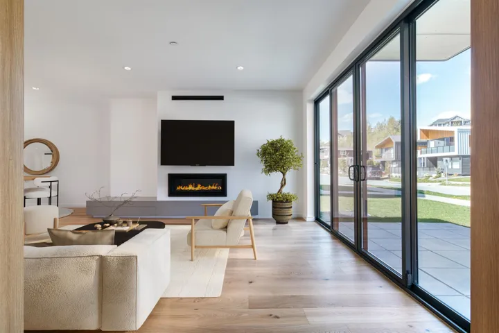 Living area with recessed lighting, light wood-type flooring, baseboards, and a glass covered fireplace