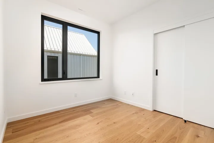 Unfurnished bedroom with wood finished floors, a closet, and baseboards