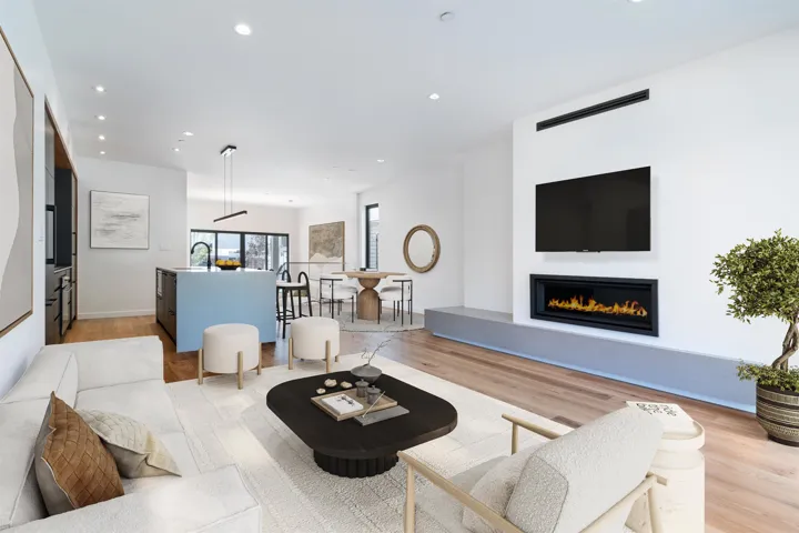 Living room with light wood-style floors, a glass covered fireplace, and recessed lighting