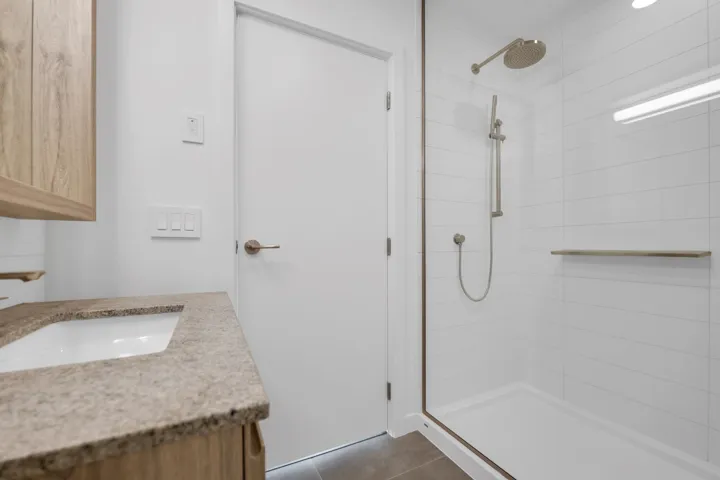 Bathroom featuring a tile shower, vanity, and tile patterned flooring