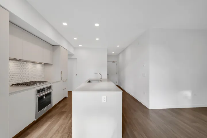 Kitchen featuring wood finished floors, stainless steel appliances, tasteful backsplash, light countertops, and recessed lighting