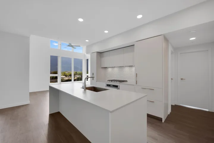 Kitchen with modern cabinets, wood finished floors, white cabinets, an island with sink, and recessed lighting
