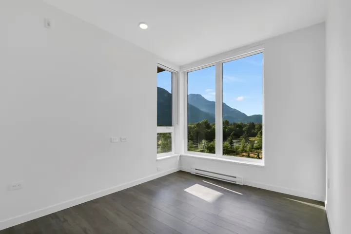 Empty room featuring a mountain view, baseboard heating, dark wood-style flooring, and recessed lighting