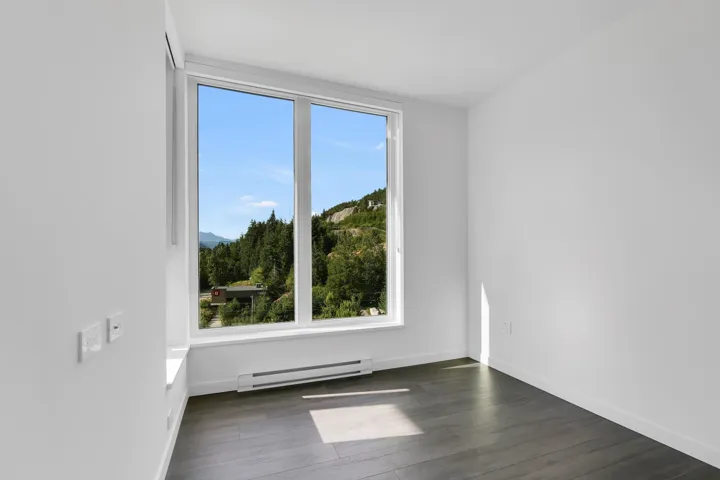 Empty room featuring baseboard heating, healthy amount of natural light, and dark wood-type flooring