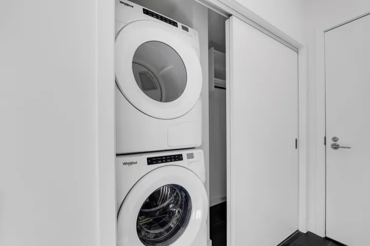 Washroom featuring stacked washer / drying machine and baseboards