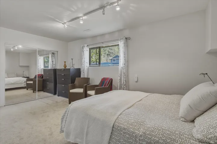 Bedroom with light colored carpet, multiple windows, rail lighting, and a closet