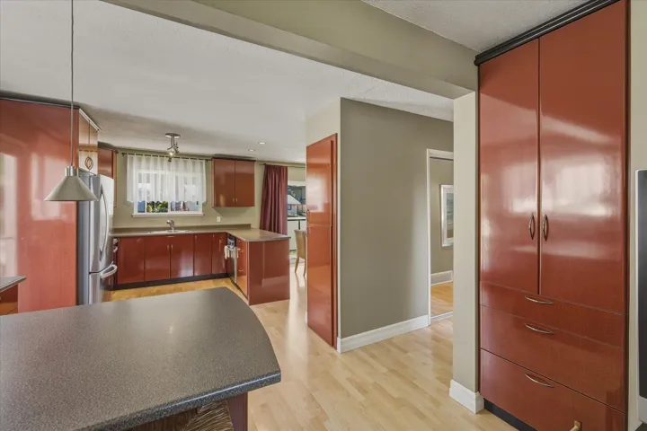 Kitchen with light wood-type flooring, freestanding refrigerator, dark countertops, and a textured ceiling
