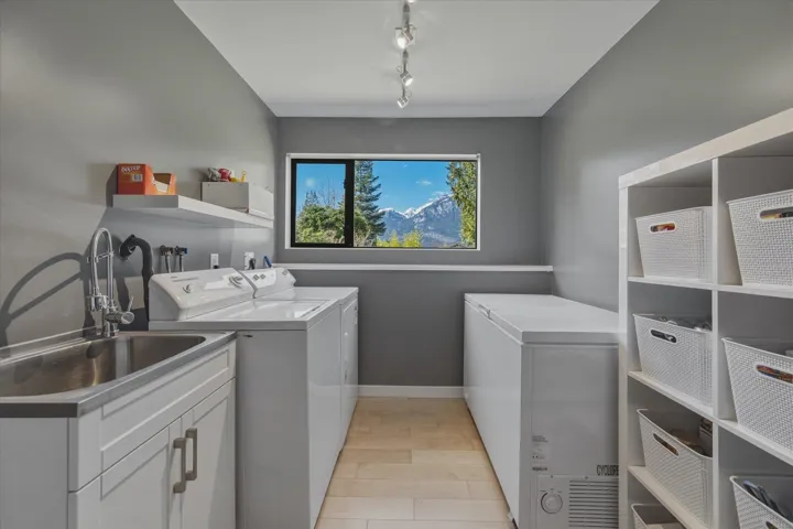 Laundry room with washer and clothes dryer, rail lighting, and light wood-style floors