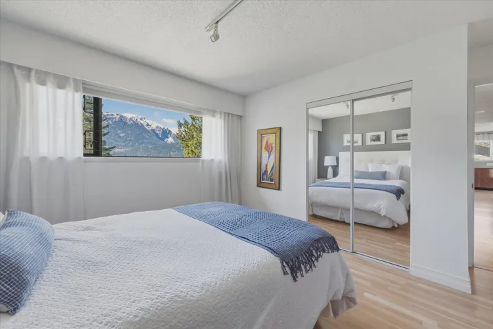 Bedroom with light wood finished floors, a textured ceiling, a closet, rail lighting, and a mountain view