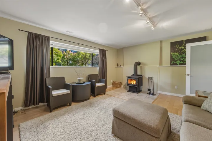 Living area with a wood stove, rail lighting, and light wood-type flooring