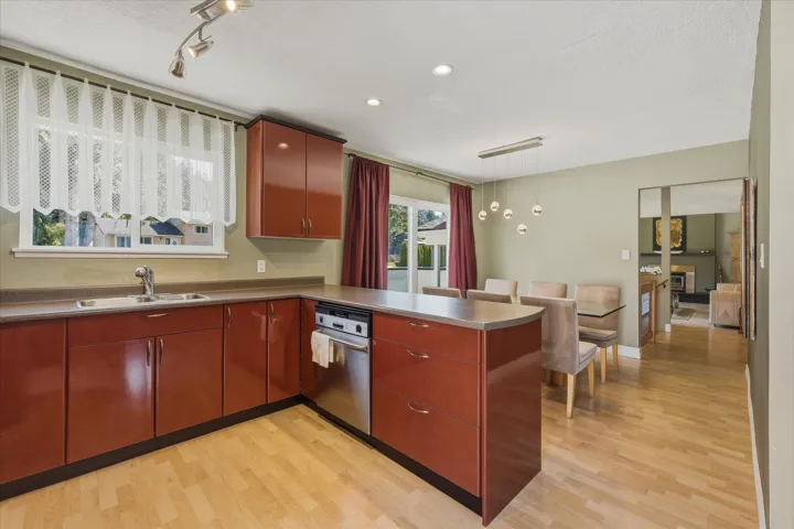 Kitchen featuring a peninsula, light wood finished floors, dark countertops, and rail lighting