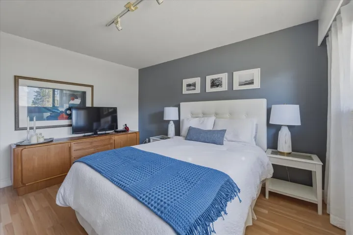 Bedroom with light wood-style flooring and rail lighting
