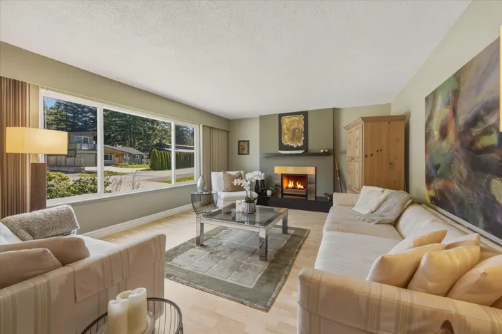 Living room featuring a warm lit fireplace, light wood-type flooring, and a textured ceiling