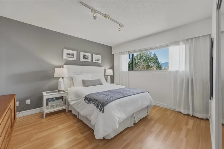 Bedroom featuring light wood-style floors, track lighting, and a textured ceiling