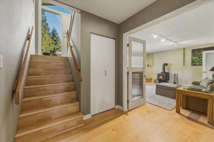 Staircase featuring a wood stove, hardwood / wood-style flooring, and track lighting