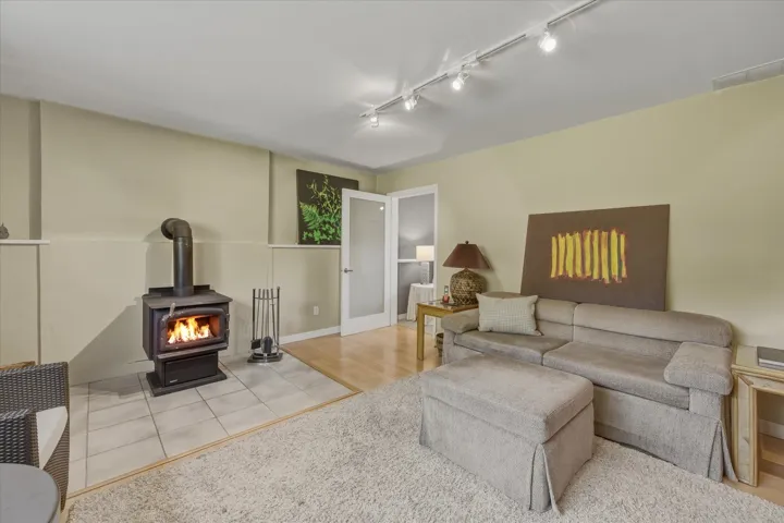 Living room featuring rail lighting, a wood stove, and light tile patterned floors