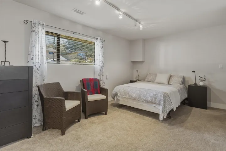Bedroom with light carpet and track lighting