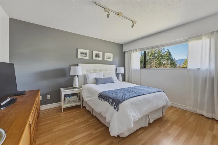 Bedroom with track lighting, light wood finished floors, and a textured ceiling