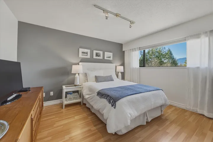 Bedroom with light wood-type flooring, track lighting, and a textured ceiling