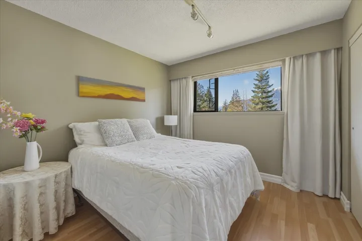 Bedroom with track lighting, light wood-style flooring, and a textured ceiling