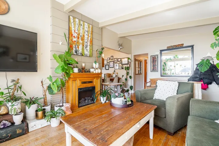 Living room featuring beam ceiling, wood finished floors, and a fireplace