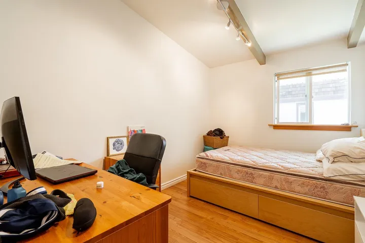Bedroom with rail lighting, light wood-style floors, and lofted ceiling