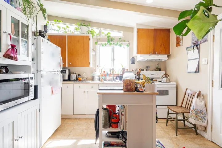 Kitchen featuring a center island, a sink, white appliances, under cabinet range hood, and light countertops