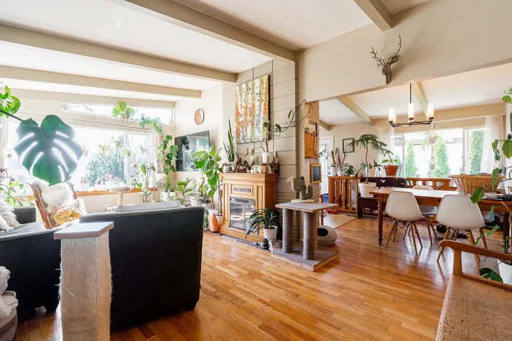Living room featuring a chandelier, light wood-style flooring, beamed ceiling, and a glass covered fireplace
