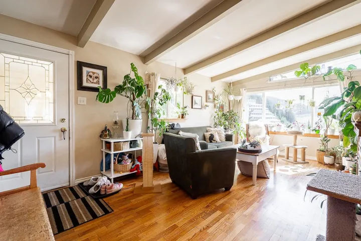 Living room with light wood-style floors, a healthy amount of sunlight, and vaulted ceiling with beams
