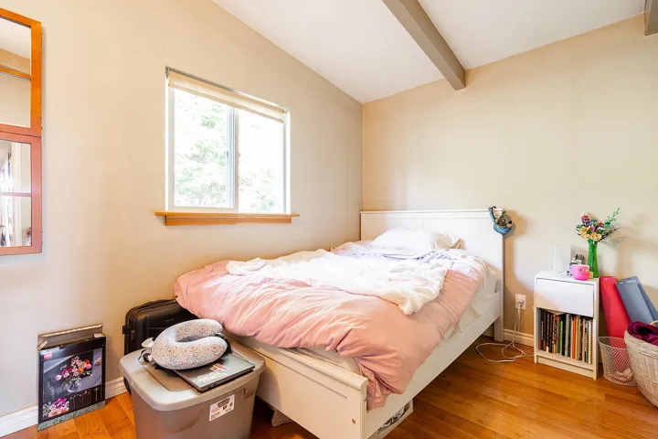 Bedroom featuring baseboards, lofted ceiling with beams, and wood finished floors
