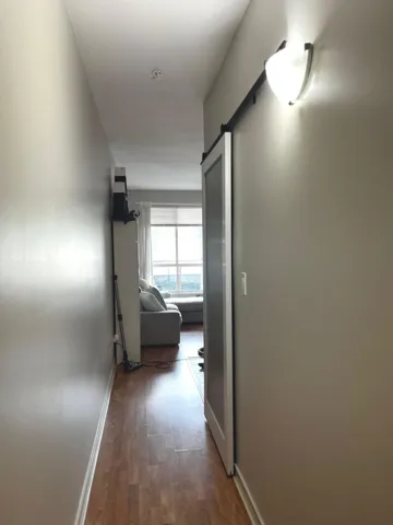 Corridor with a barn door and dark wood-type flooring