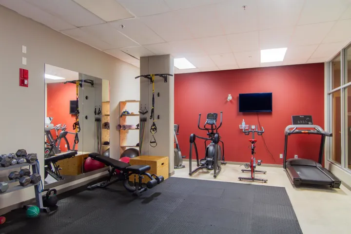 Gym with a paneled ceiling and baseboards