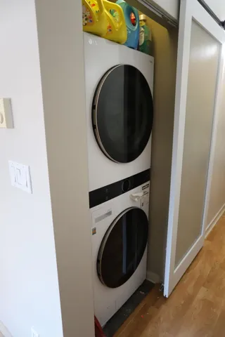 Laundry room with wood finished floors and stacked washer and clothes dryer